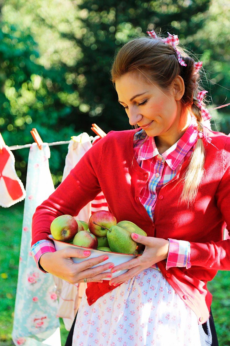 Frau mit geerntetem Obst im spätsommerlichen idyllischen Garten