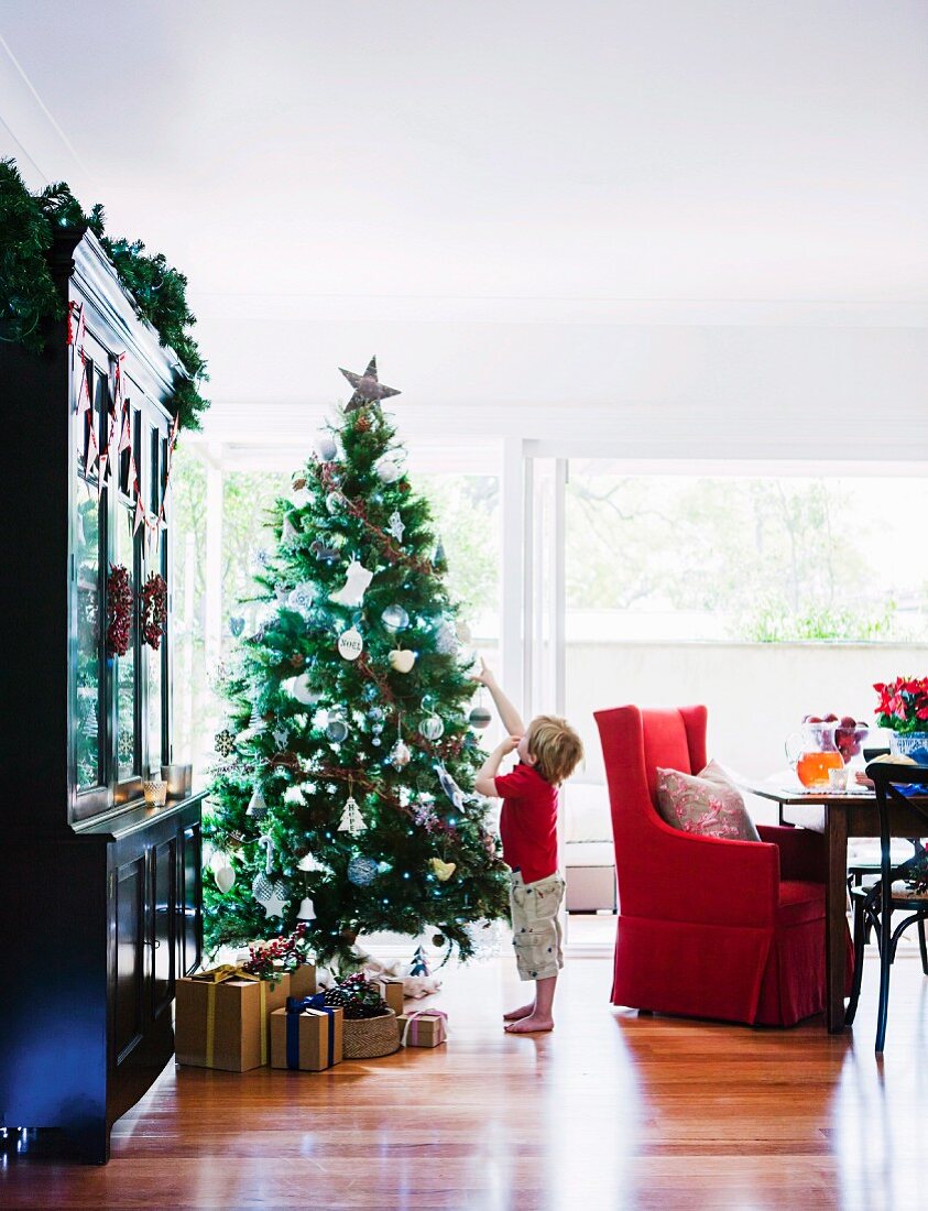 Kleiner Junge bestaunt Stern am Weihnachtsbaum