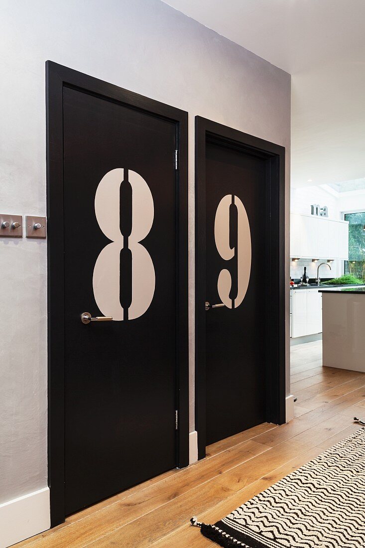 Enormous numbers on black-painted doors in open-plan hallway