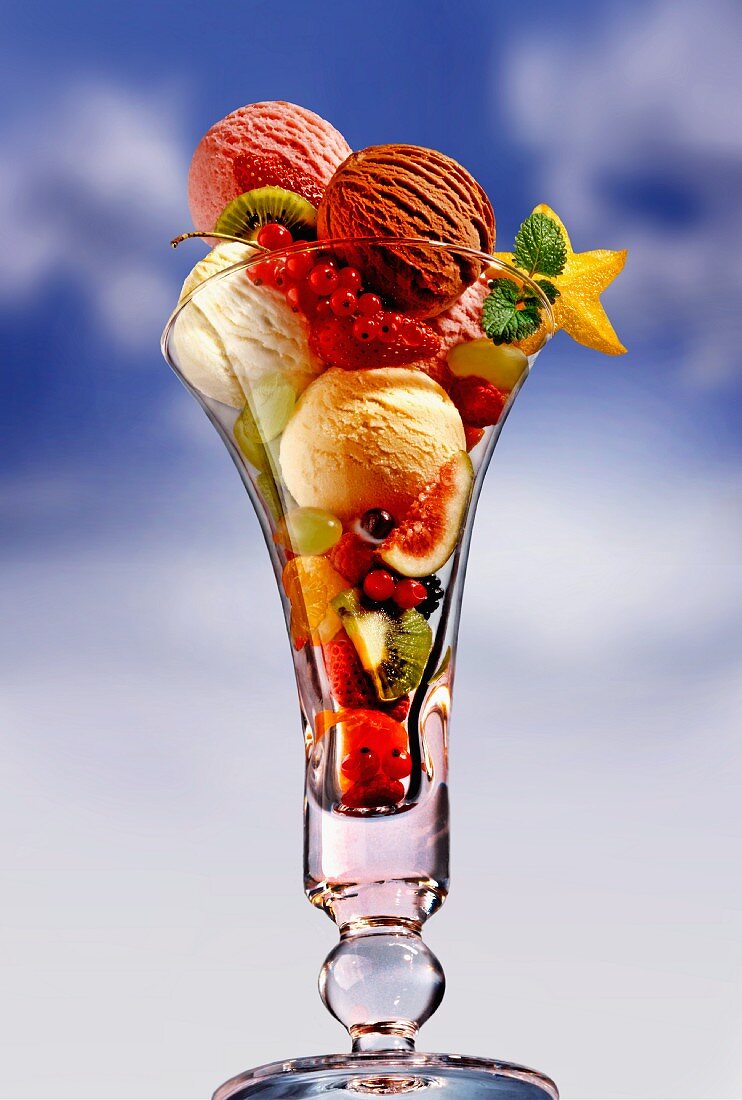An ice cream sundae with fresh fruits against a cloudy sky
