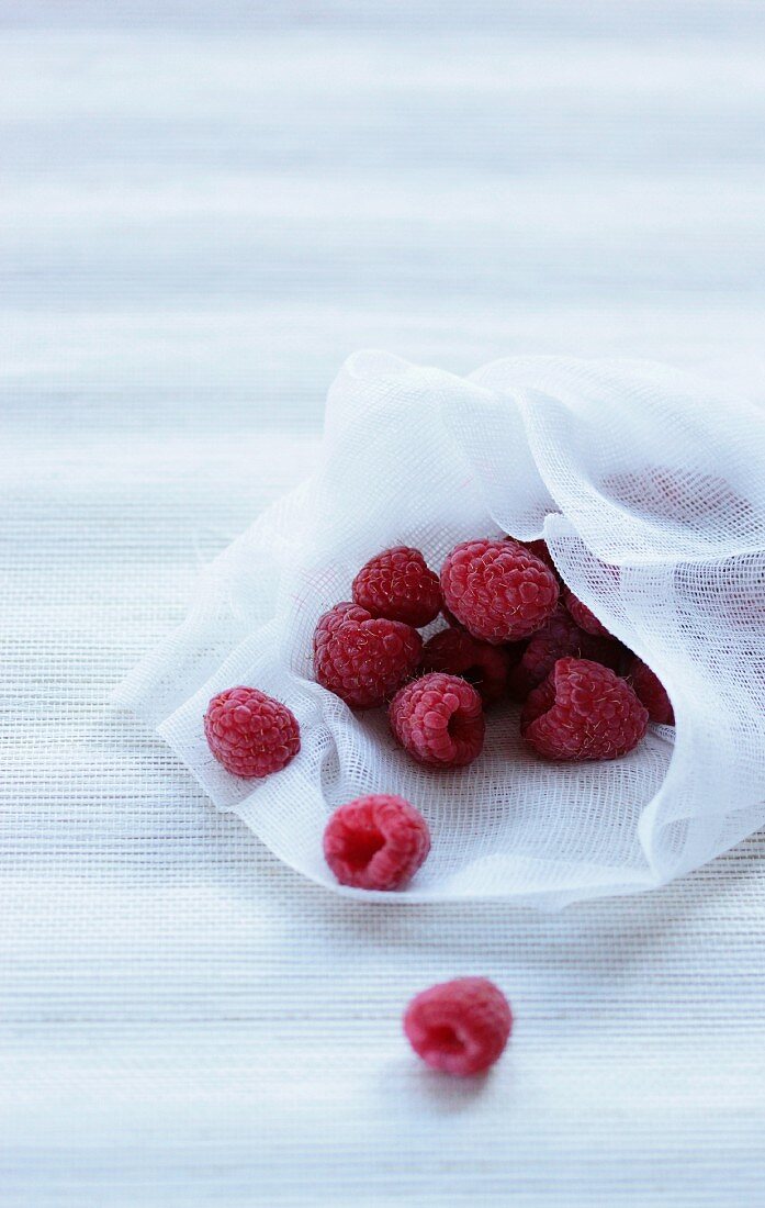 Fresh raspberries on a piece of white fabric