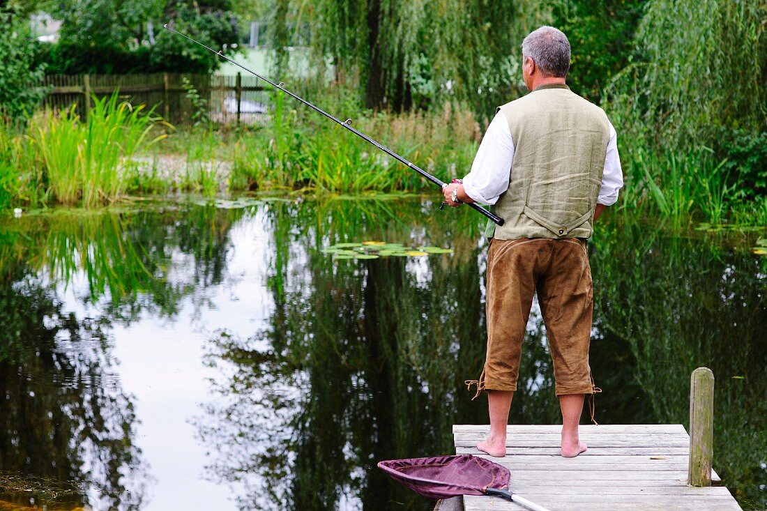Angler auf Holzsteg an Teich