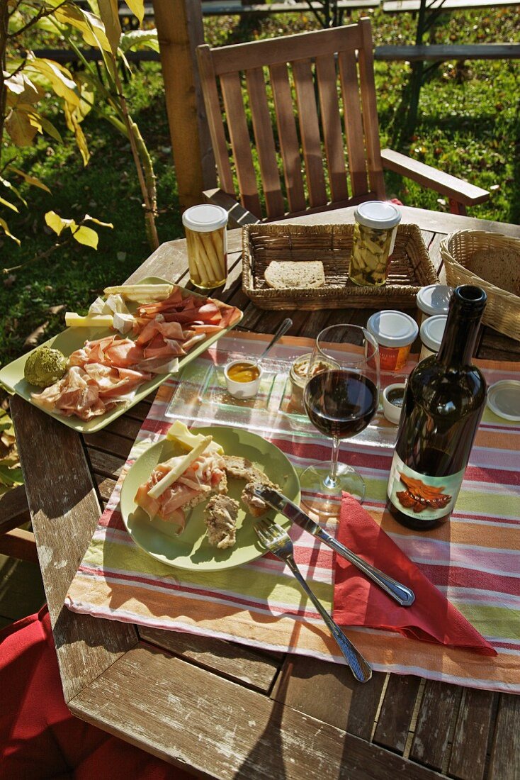 A snack with red wine on a garden table