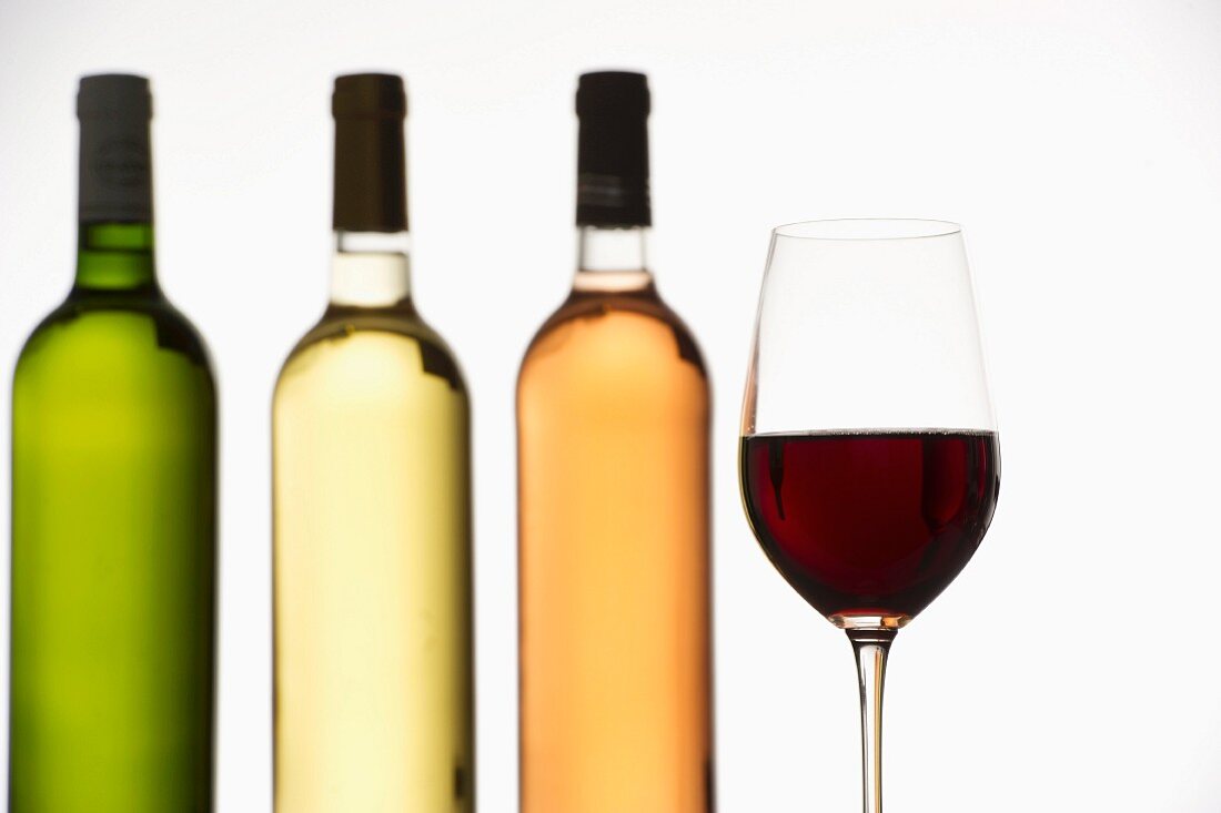 Vier verschiedene Bordeaux-Weine in Flaschen & Weinglas