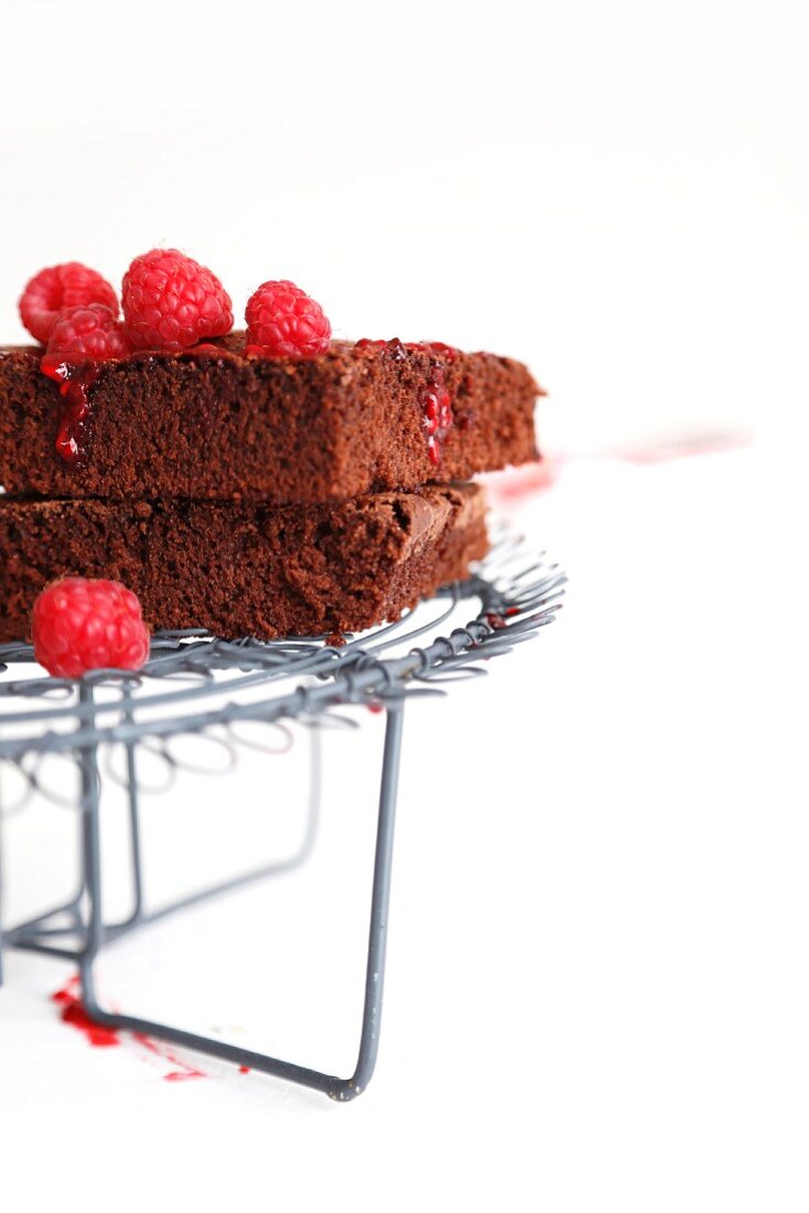 Two brownies with raspberry sauce on a wire rack