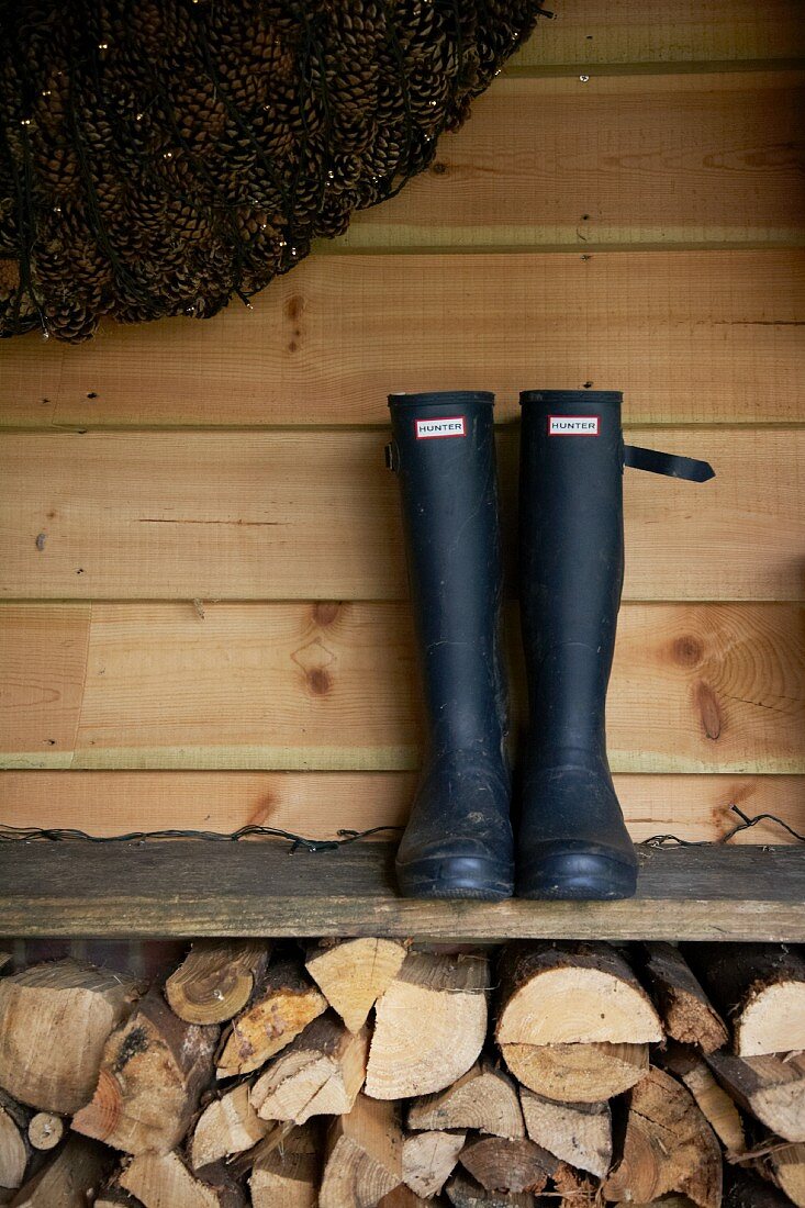 Ein Paar Stiefel auf Ablagebrett über Brennholzstapel