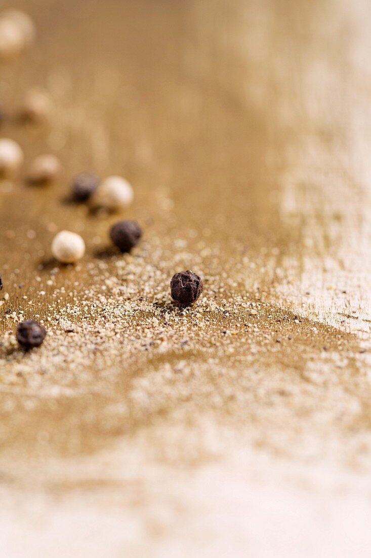 Black and white peppercorns on ground pepper