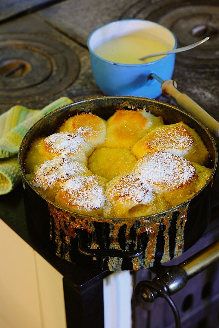 Dampfnudeln (steamed, sweet yeast dumpling) dusted with icing sugar in a pot