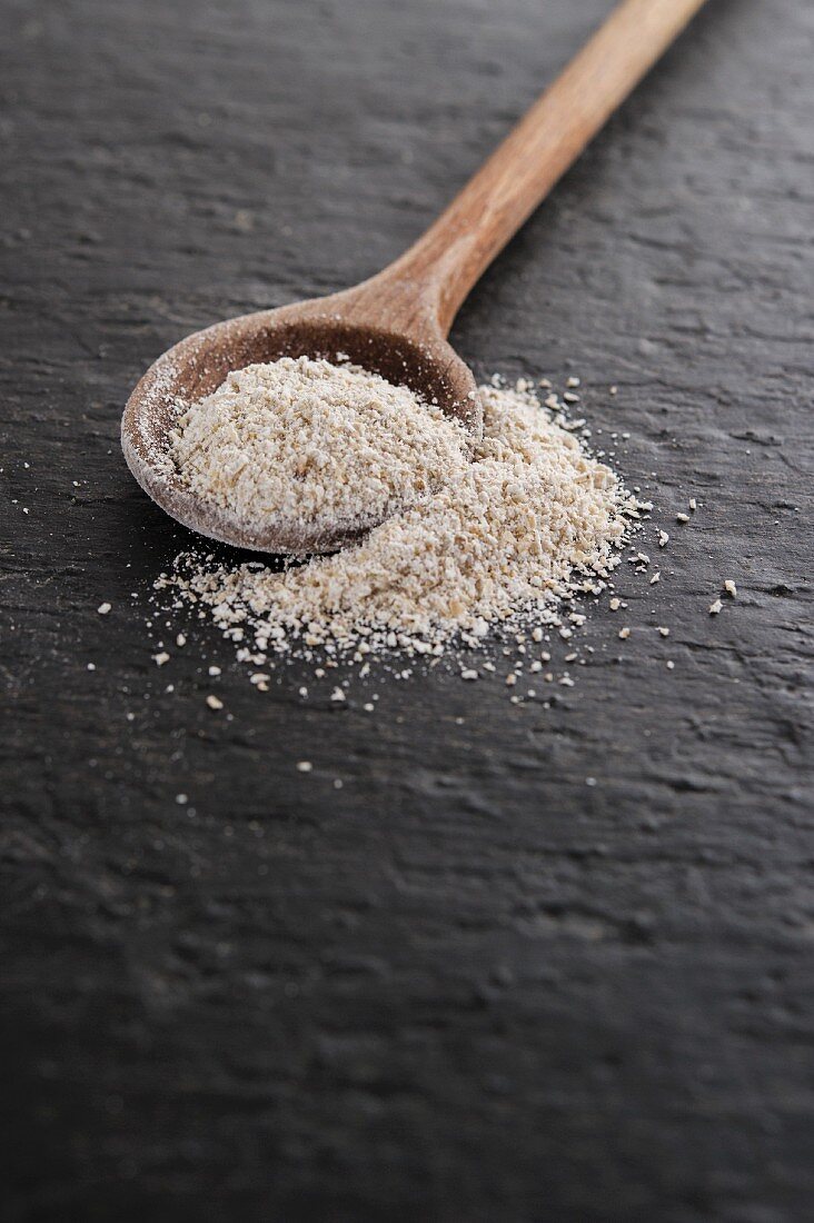 Spelt semolina on and next to a wooden spoon