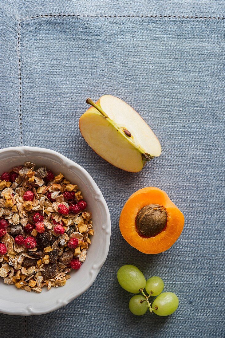 A bowl of muesli next to fresh fruit