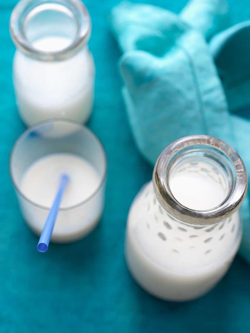 Milk in a drinking glass and in glass bottles
