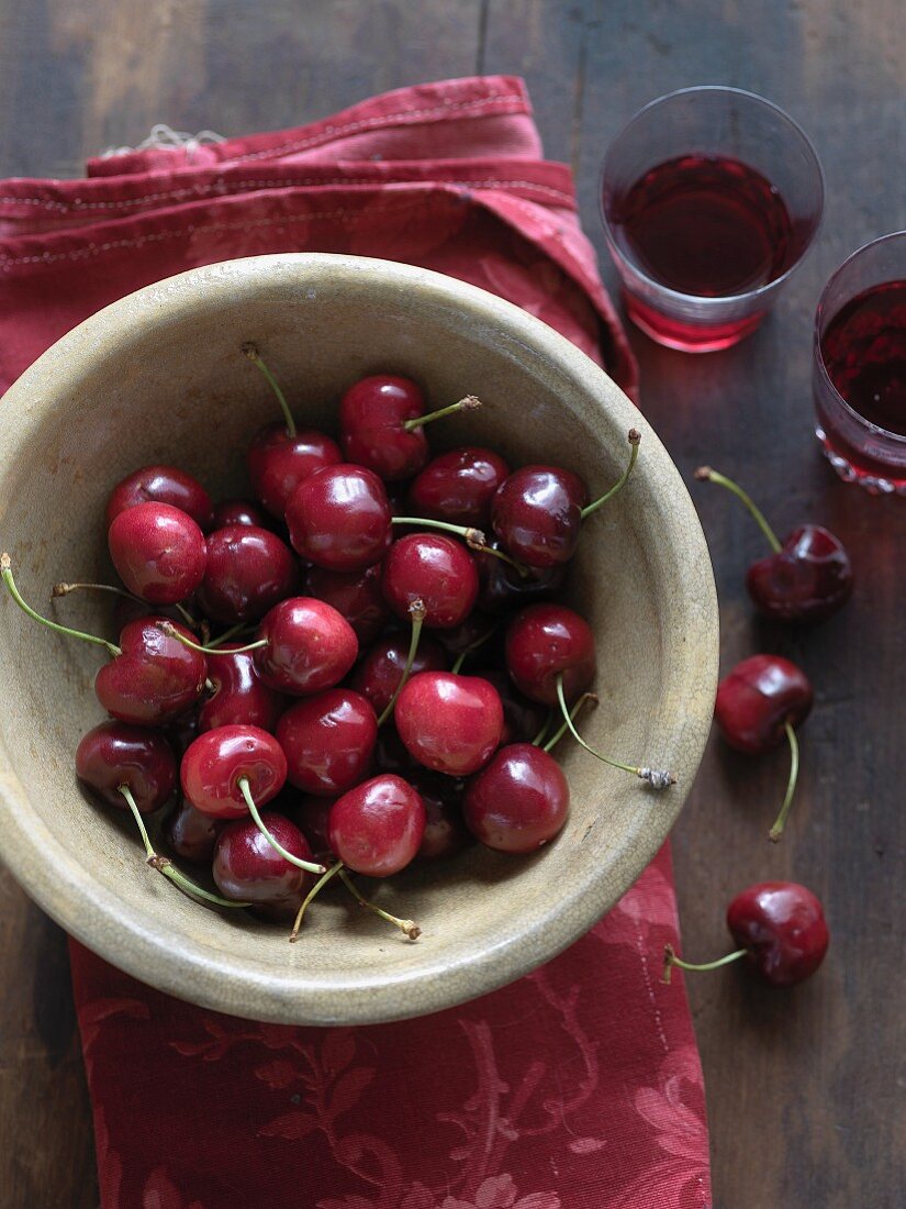 A bowl of fresh cherries and glasses of cherry juice