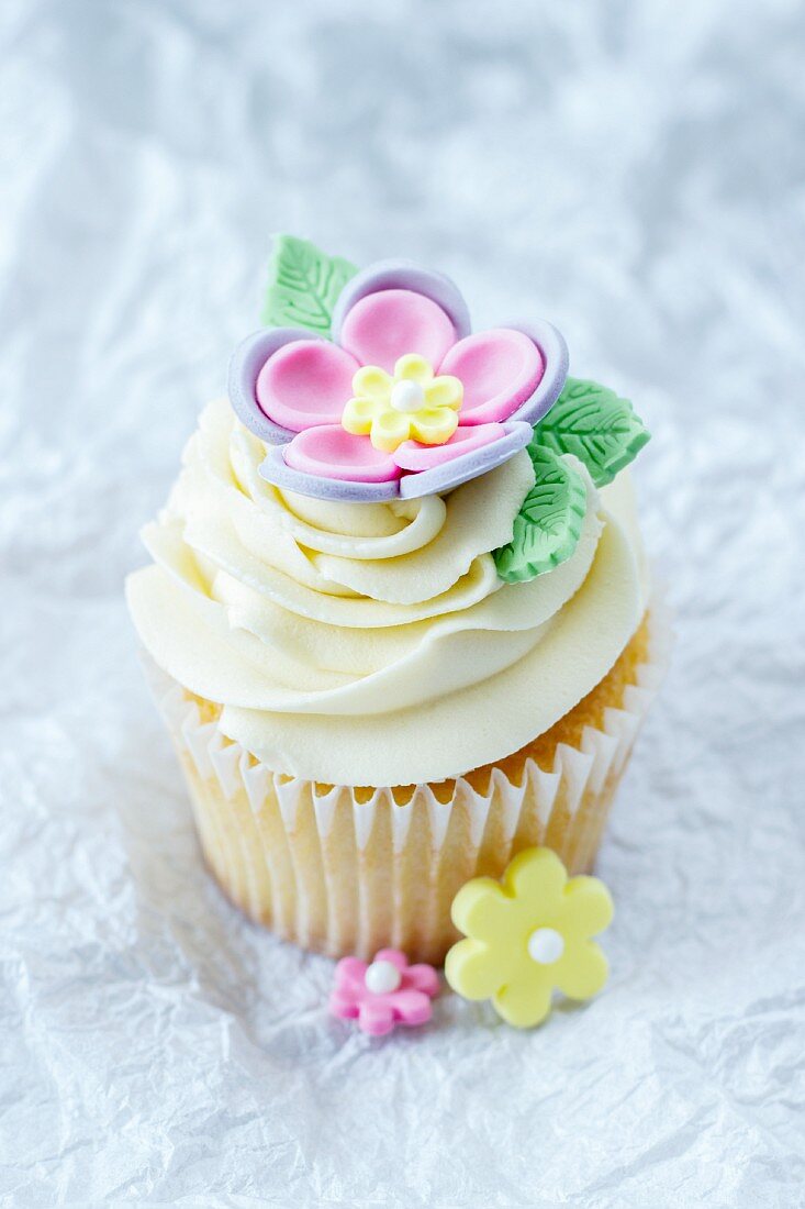 A cupcake topped with vanilla cream and decorated with a sugar flower
