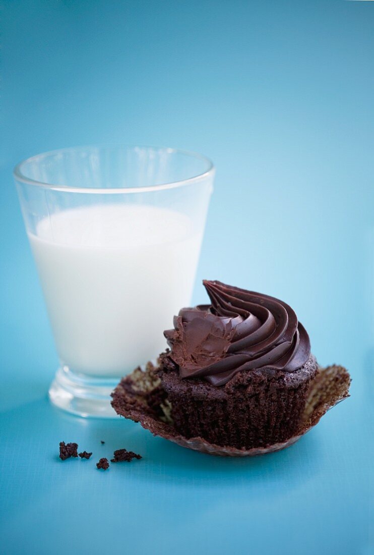 A chocolate cupcake and a glass of milk
