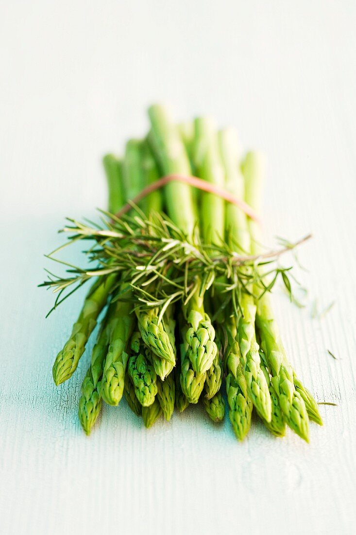 A bunch of green asparagus and a sprig of rosemary