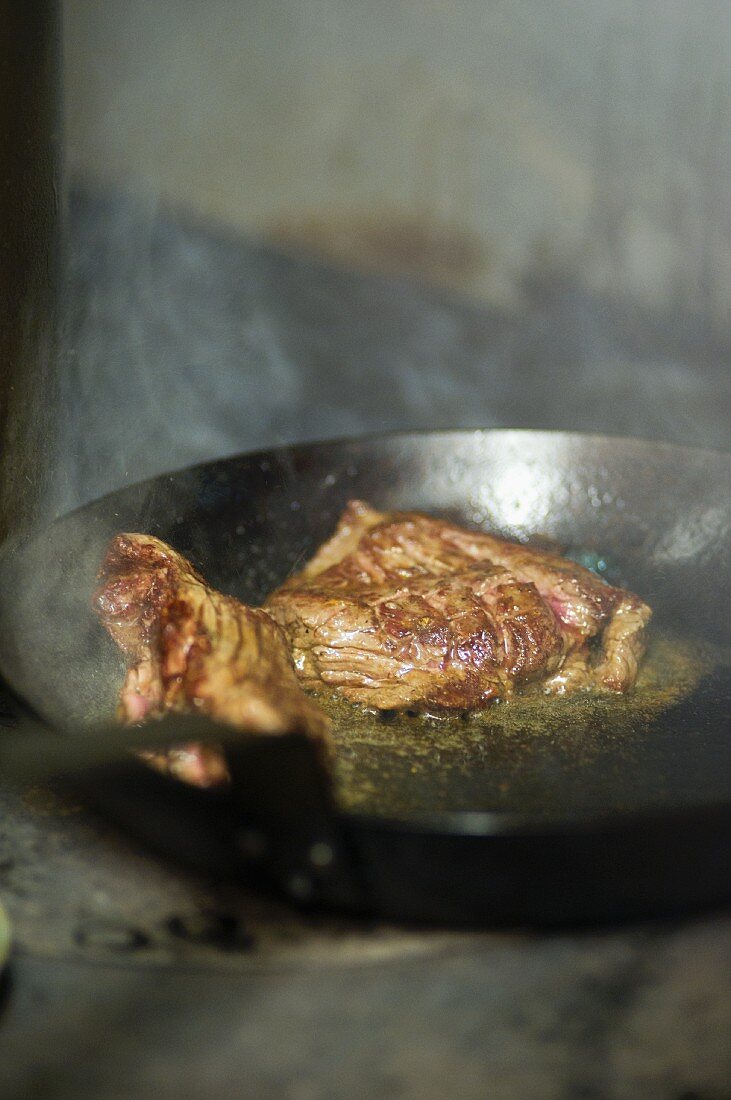 Beefsteak being fried in a pan