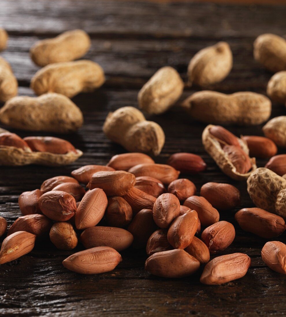 Peanuts, shelled and unshelled, on a wooden surface