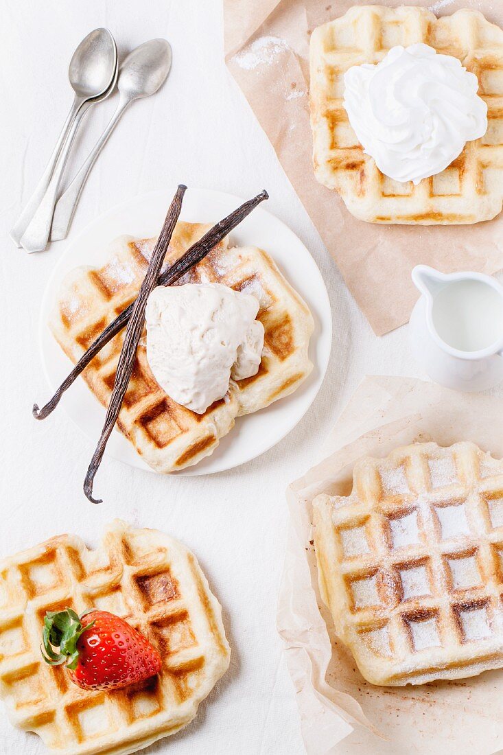 Belgian waffles served with ice cream, strawberries, whipped cream and vanilla pods