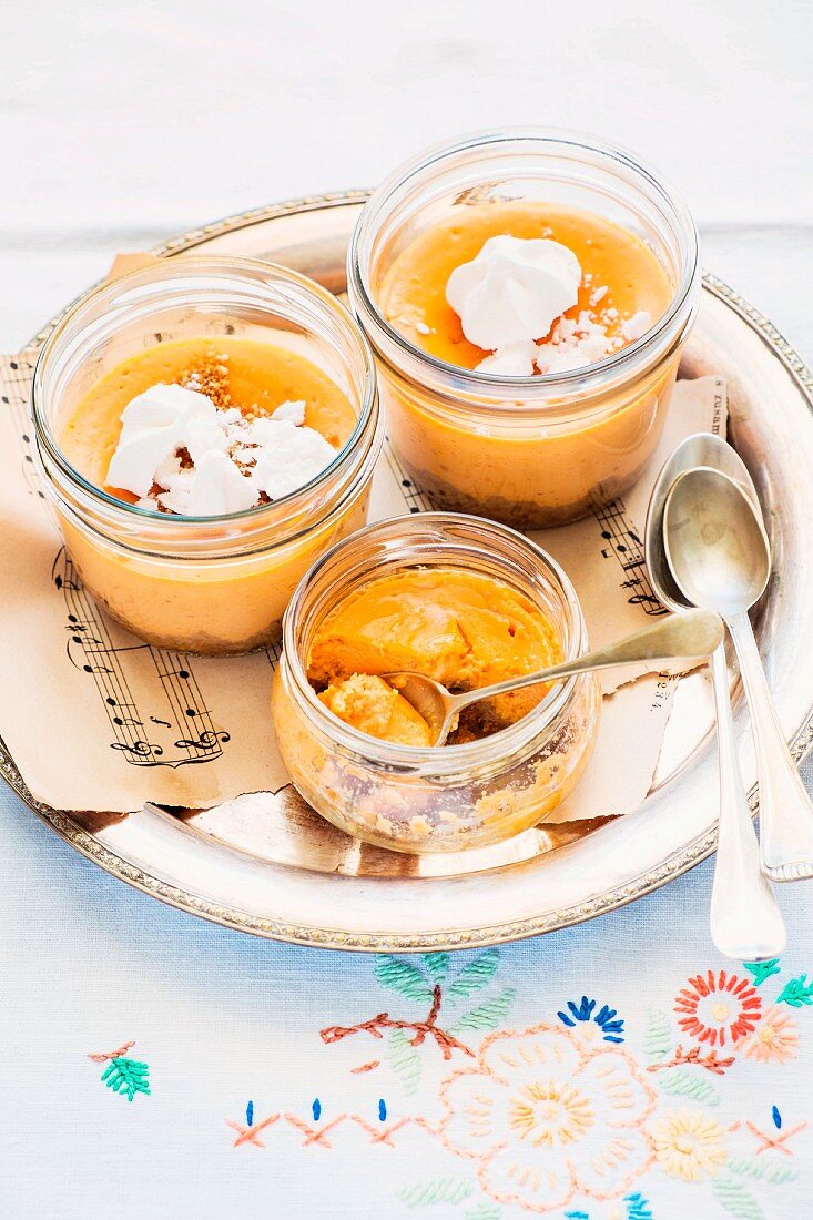Cheese and pumpkin cakes with gingerbread bases in glasses garnished with ricotta