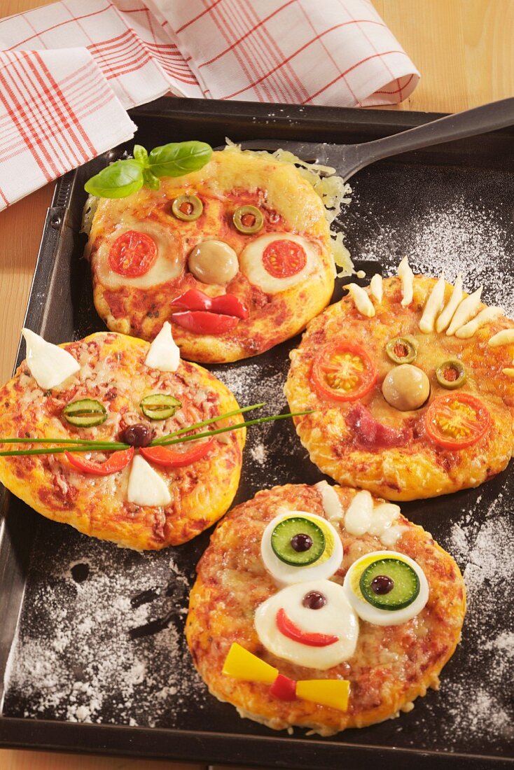 Minipizzen mit lustigen Gesichtern für die Kinderparty