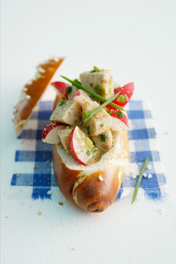 A lye bread roll filled with white sausage salad