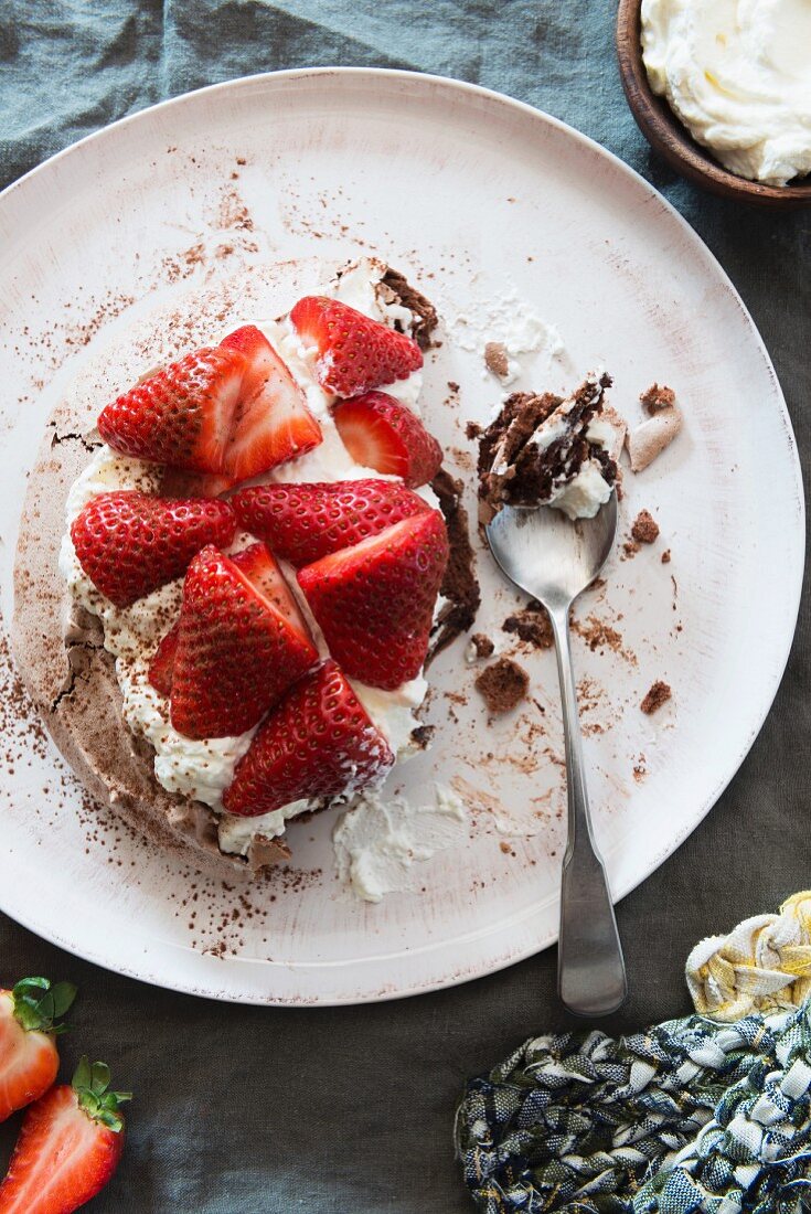 Chocolate pavlova with strawberries and cream with a bite taken out
