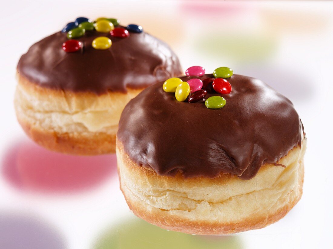 Chocolate glazed doughnuts decorated with coloured chocolate beans