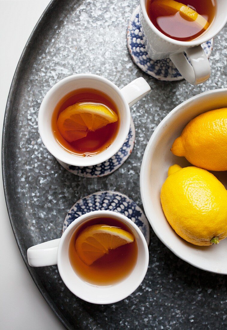 Three cups of lemon tea and fresh lemons