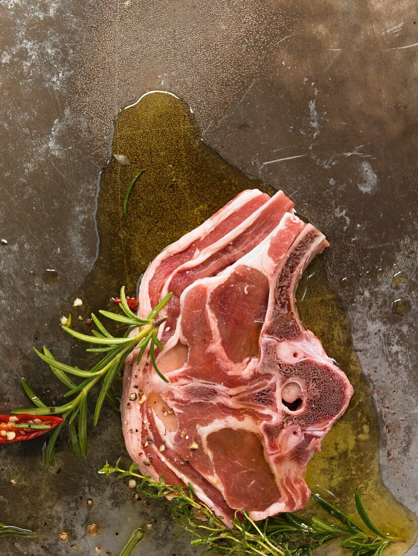 Saddle of lamb in oil on a metal plate with herbs and spices
