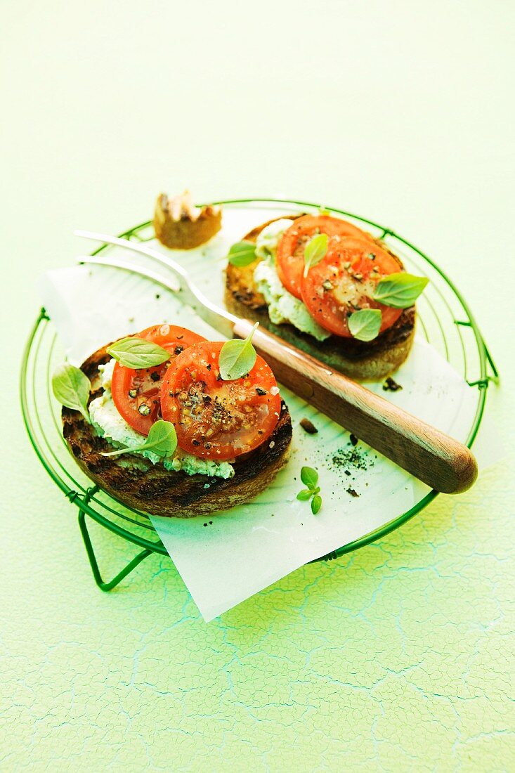 Crostini topped with pesto, cream cheese and tomatoes