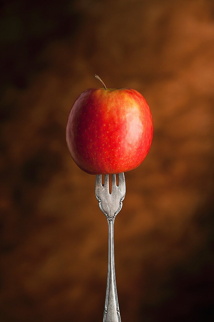 Aufgespiesster roter Apfel auf einer Gabel