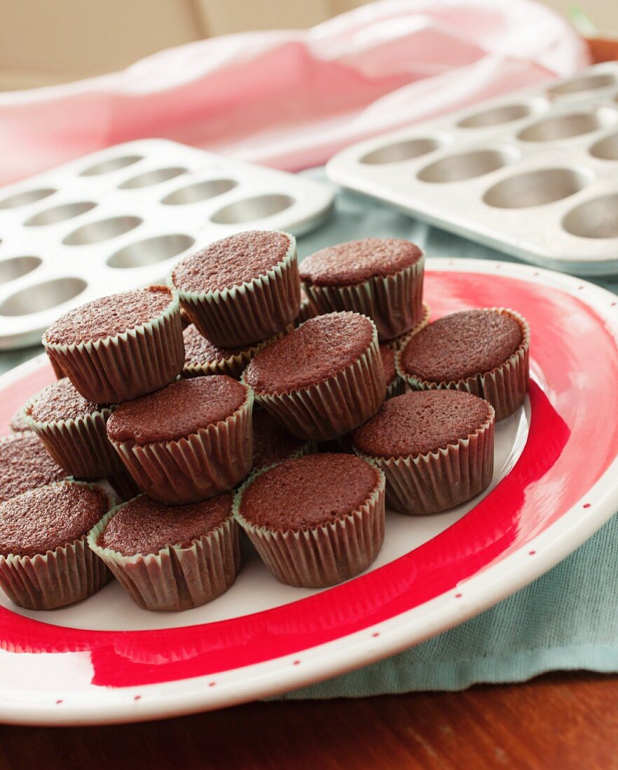 Chocolate cupcakes waiting to be decorated on a red and white plate