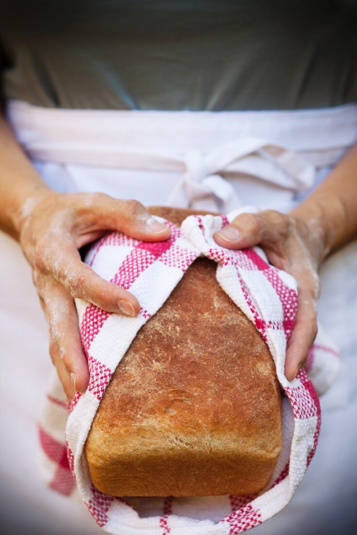 A woman holding a loaf of freshly baked bread
