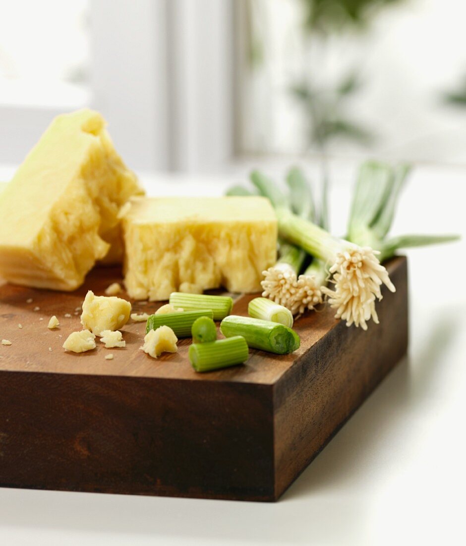 Cheese and spring onions on a chopping board