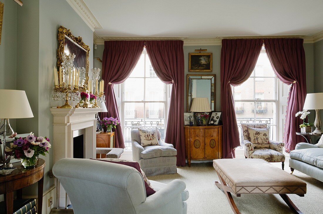 Traditional living room with ottoman and draped curtains on floor-to-ceiling windows