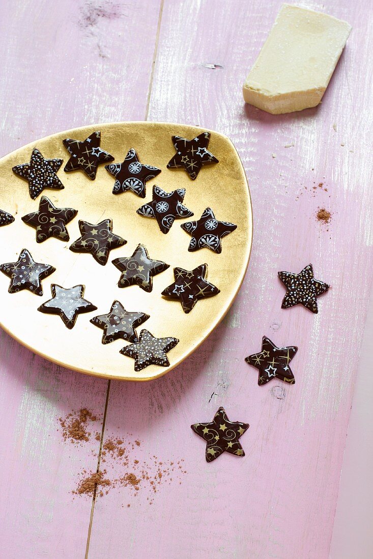 Dark chocolate stars with light decorations on a golden plate