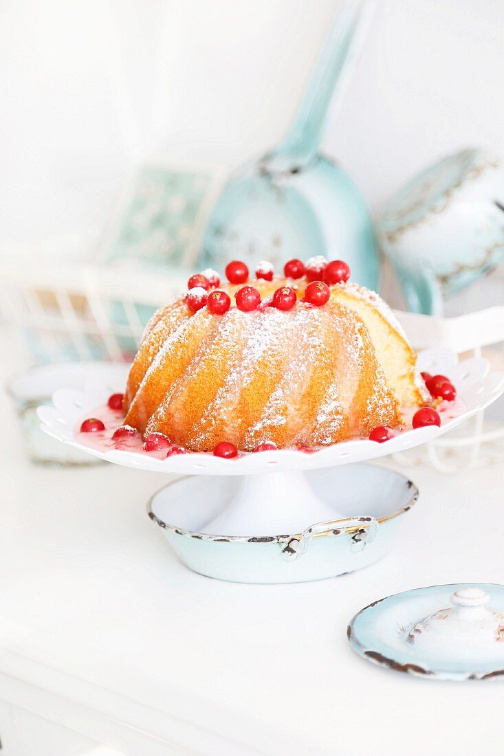Bundt cake with redcurrant sauce on a white cake stand