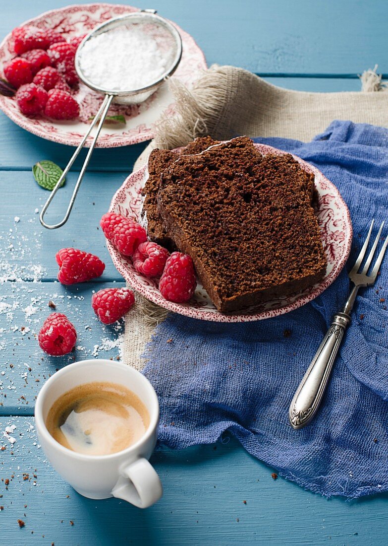Chocolate cake with raspberries and icing sugar with a cup of coffee