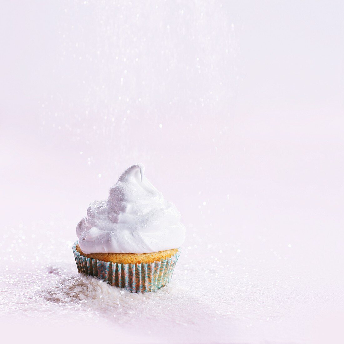 A cupcake topped with cream and sprinkle with sugar