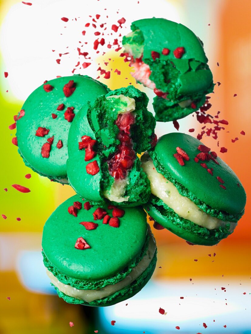 Green macaroons filled with a light cream and pomegranate seeds