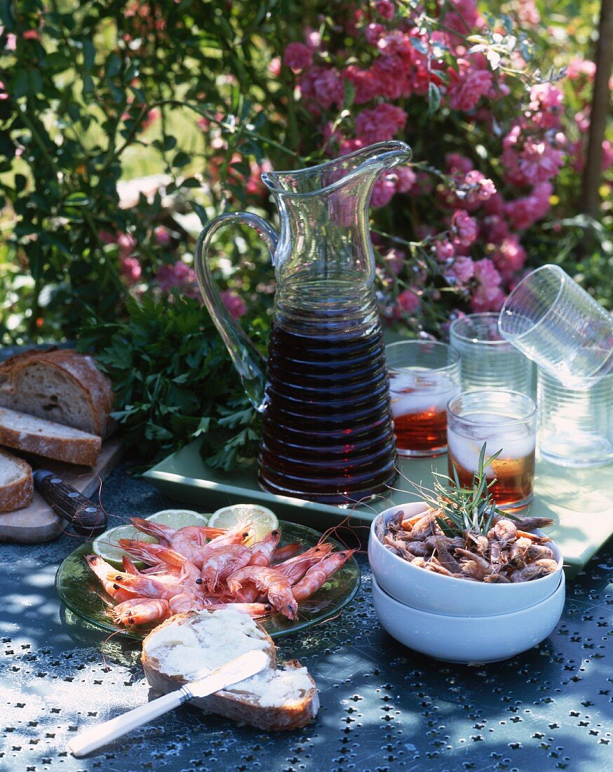 Seafood, bread and drinks on a table in a garden