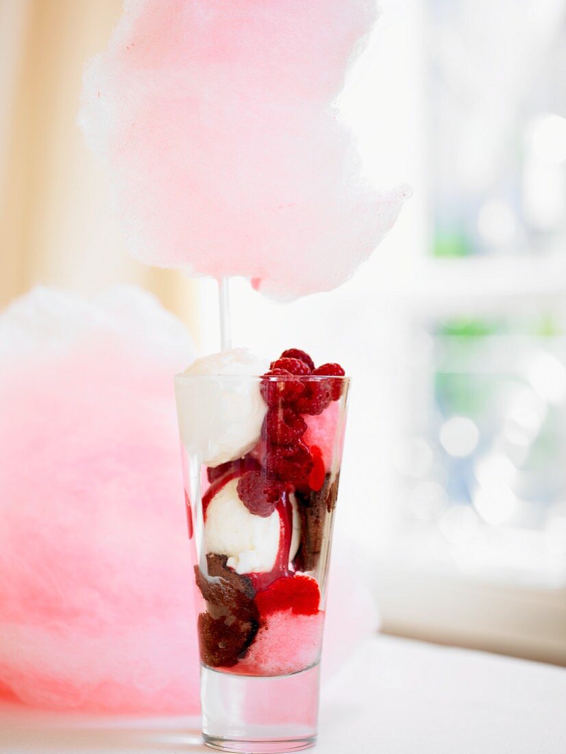 An ice cream dessert with fresh strawberries and pink candyfloss