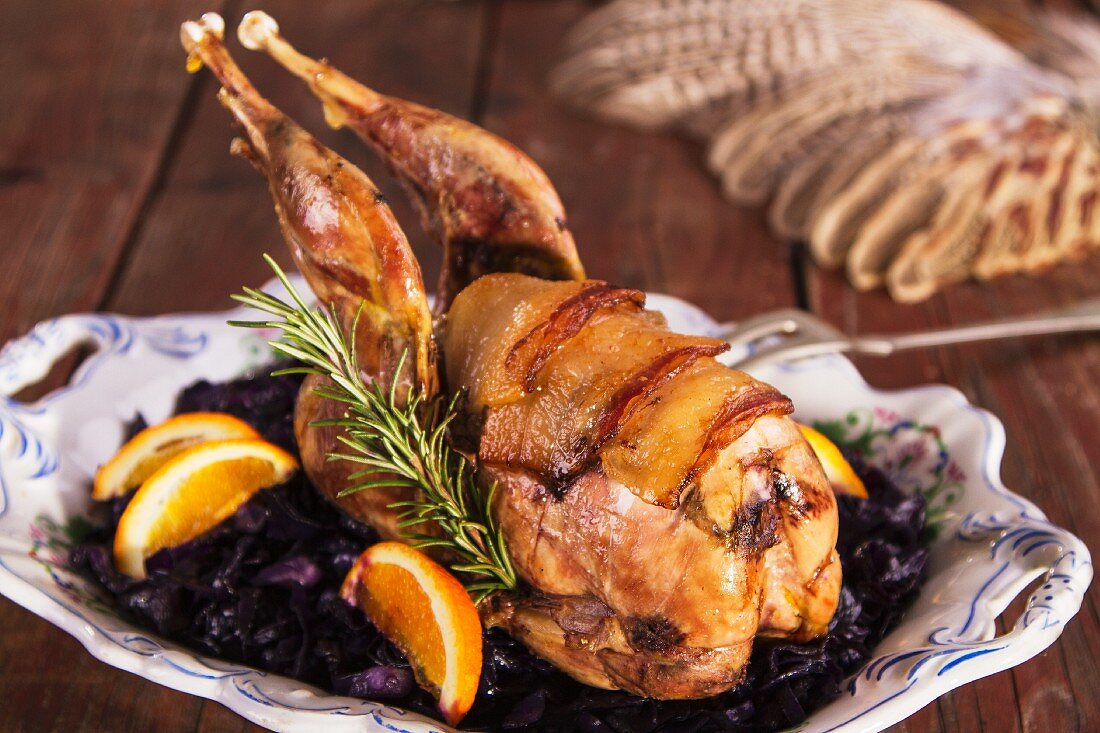 Pheasant wrapped in bacon with oranges and red cabbage