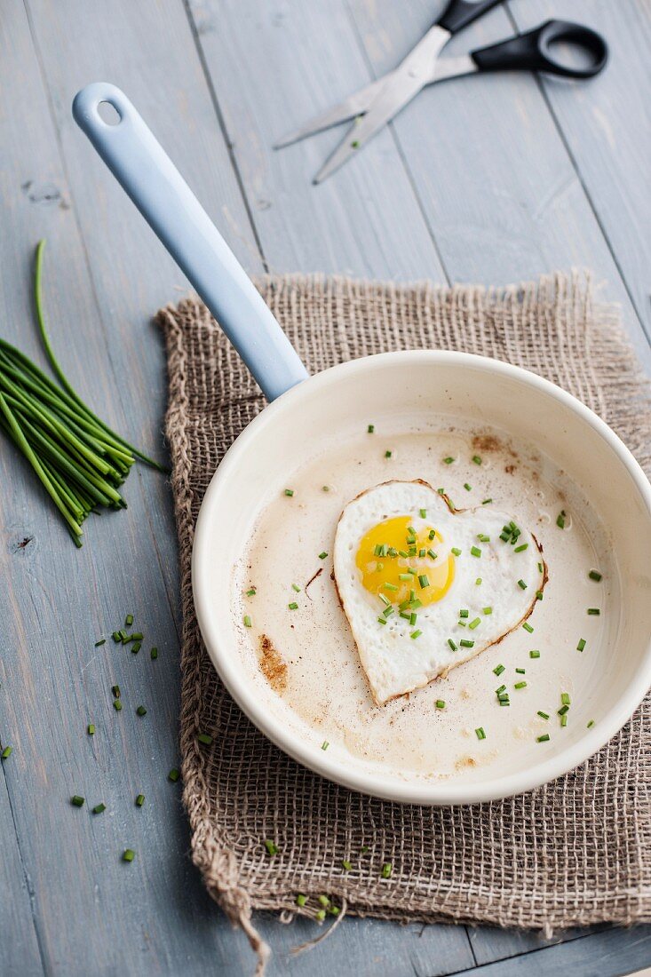 A heart-shaped fried egg with chives