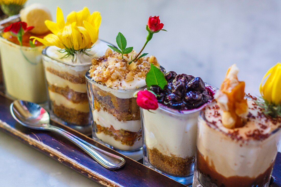 Various cream desserts iin glasses decorated with flowers