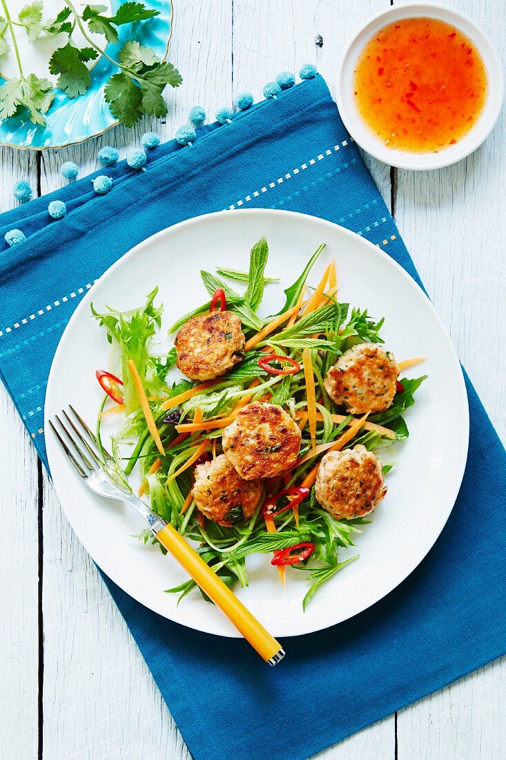 Fish cakes on a bed of salad with chilli sauce (Thailand)