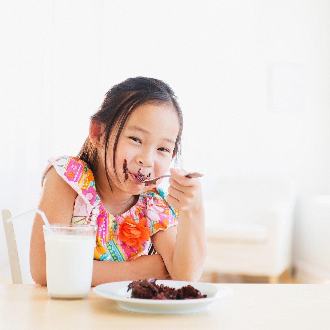 A little girl eating a slice of chocolate cake