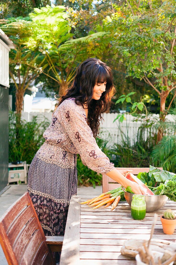 Junge Frau legt Gemüse auf den Gartentisch