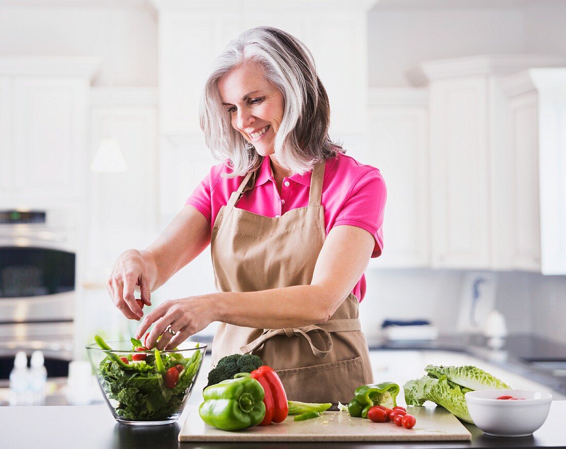 Frau bereitet Salat in der Küche zu