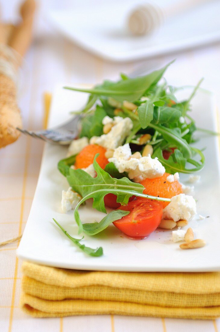 Cherry tomato salad with melon, feta cheese and rocket